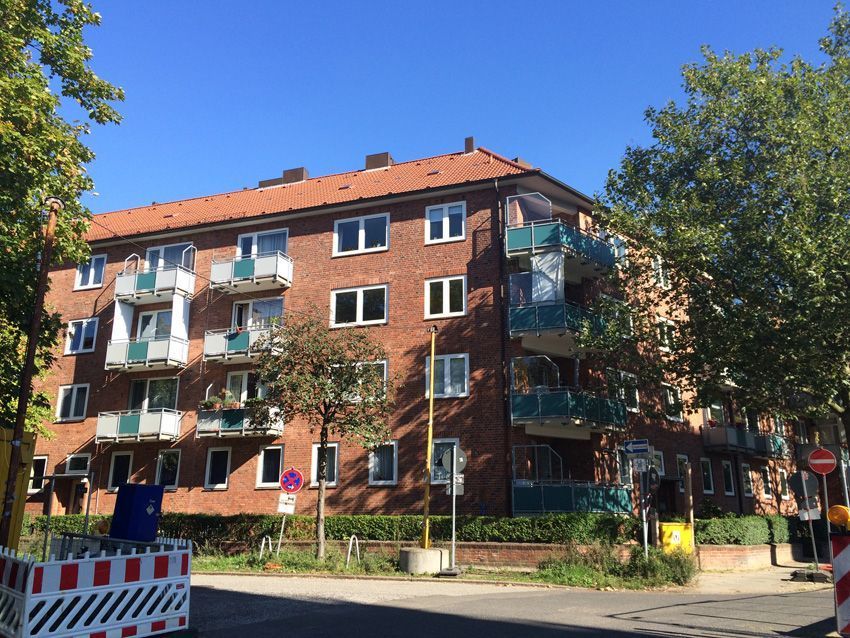 Ein Backstein-Mehrfamilienhaus mit Balkonen und einem roten Dach