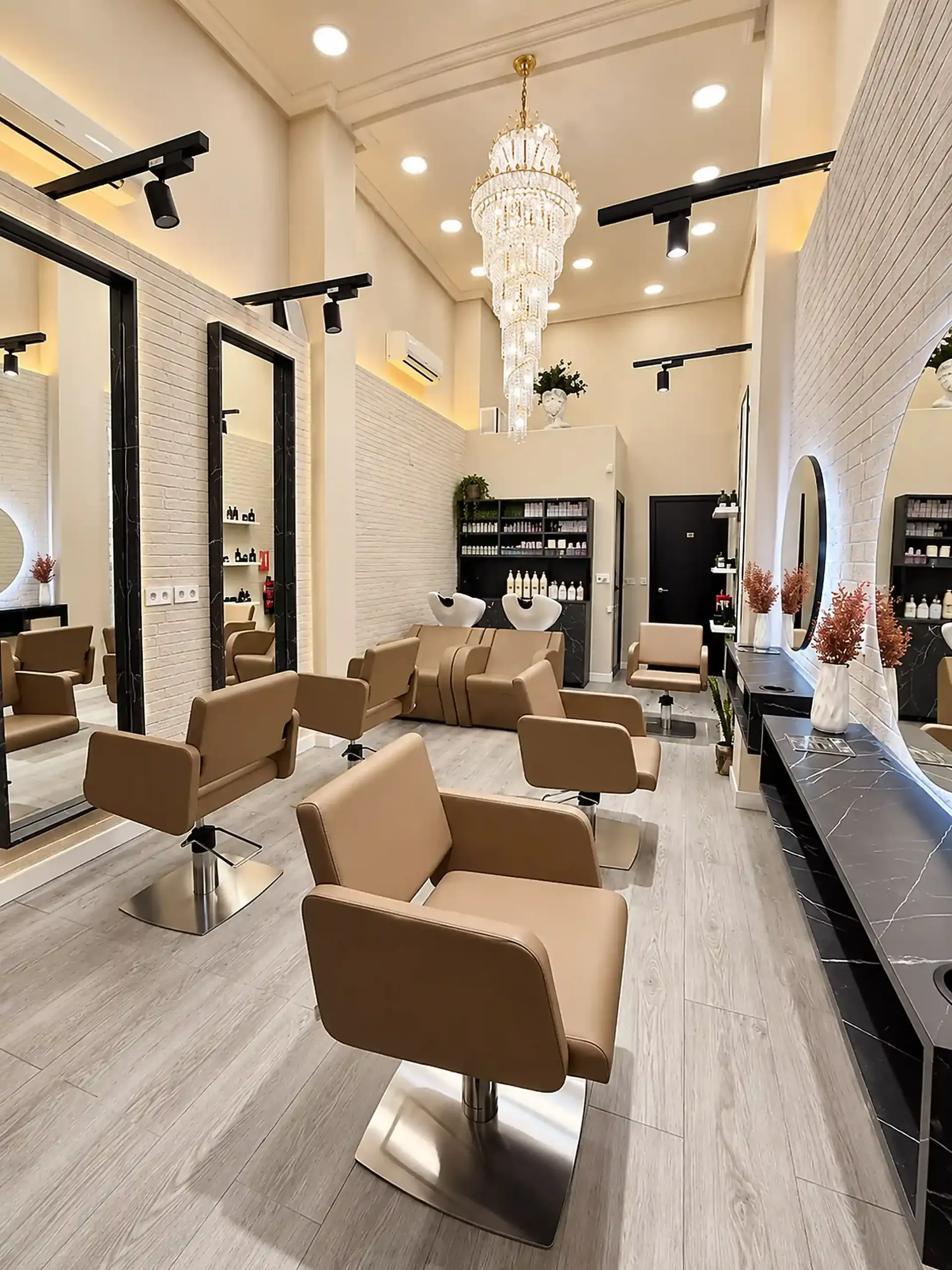 Interior moderno de salón con sillones de peluquería beige, espejos, lámparas de araña y detalles en negro
