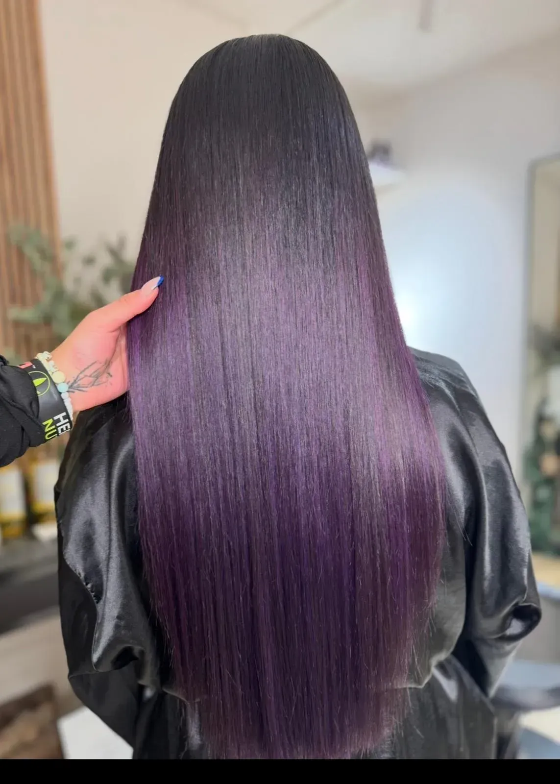 Cabello negro, largo y liso, con las puntas en degradado morado oscuro, visto desde atrás en interiores.