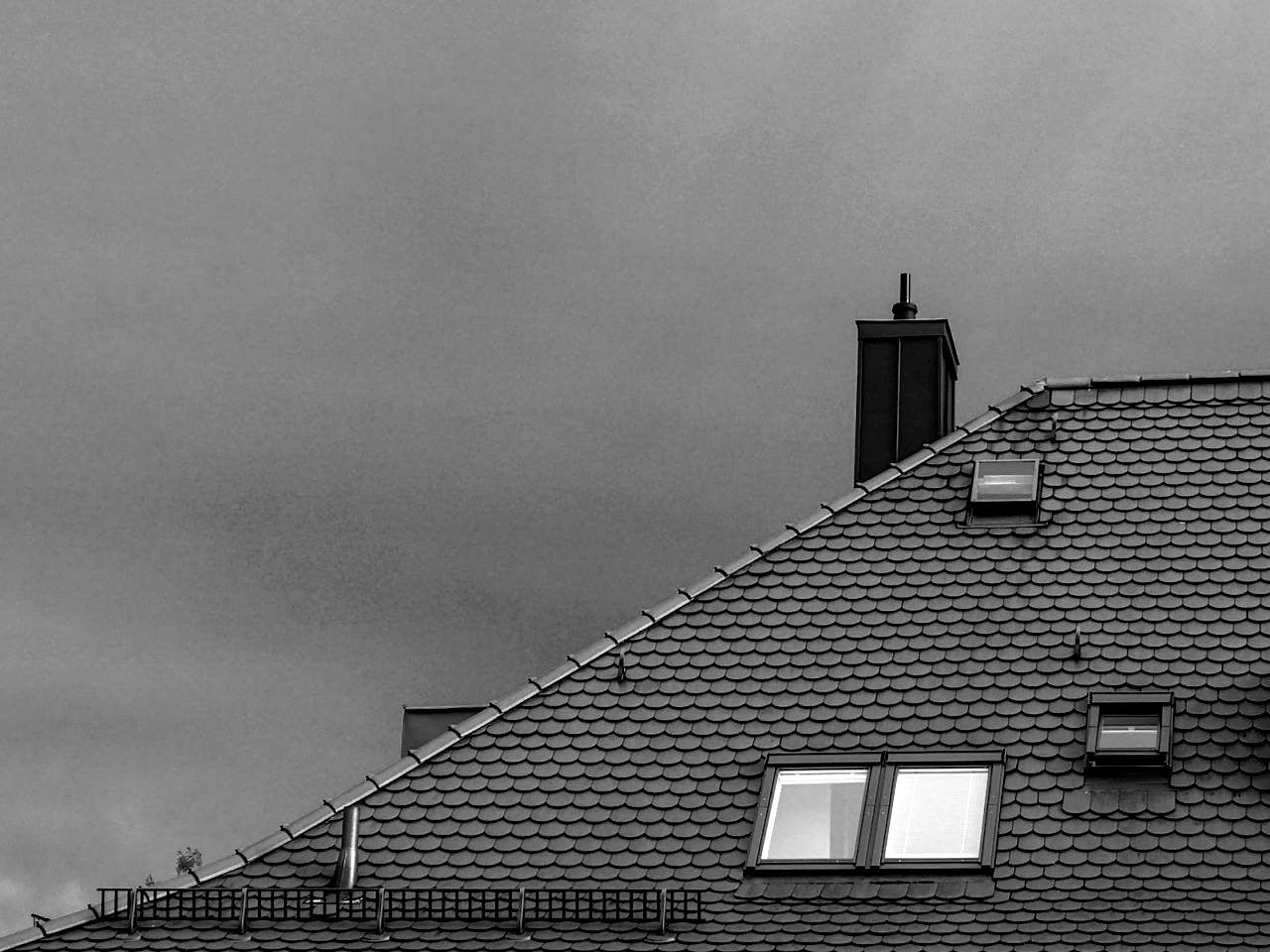 Une photo en noir et blanc d'une maison en briques avec une cheminée sur le toit.
