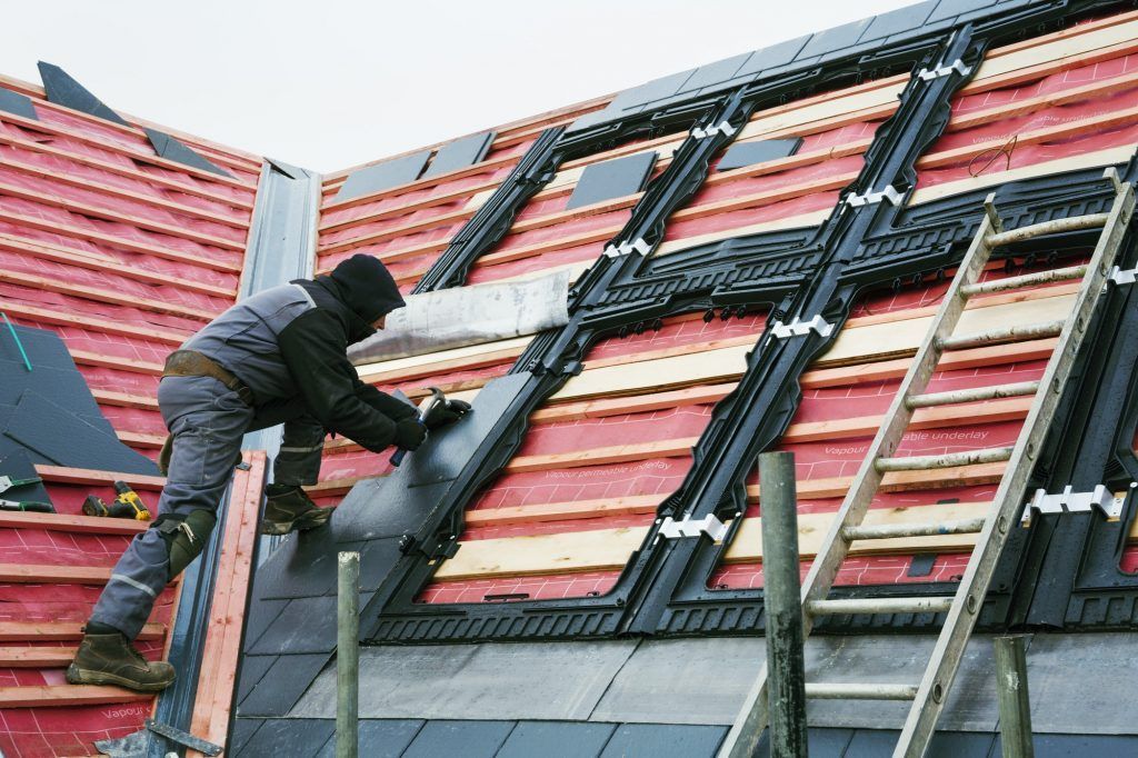 Un homme travaille sur le toit d'un immeuble.