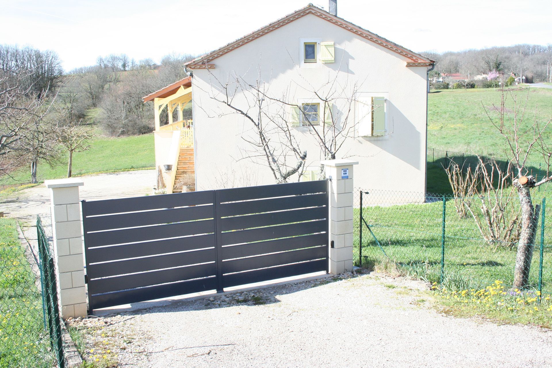 Portail gris avec maison blanche