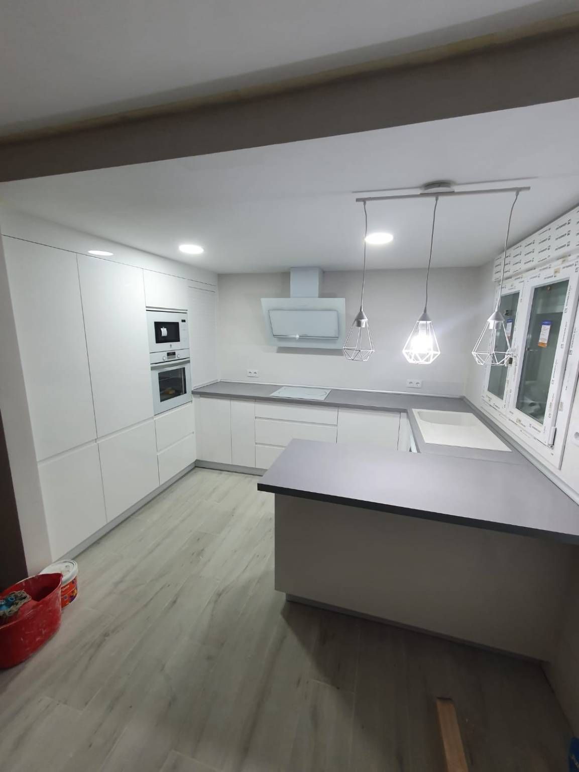 Una cocina con gabinetes blancos y una encimera gris.