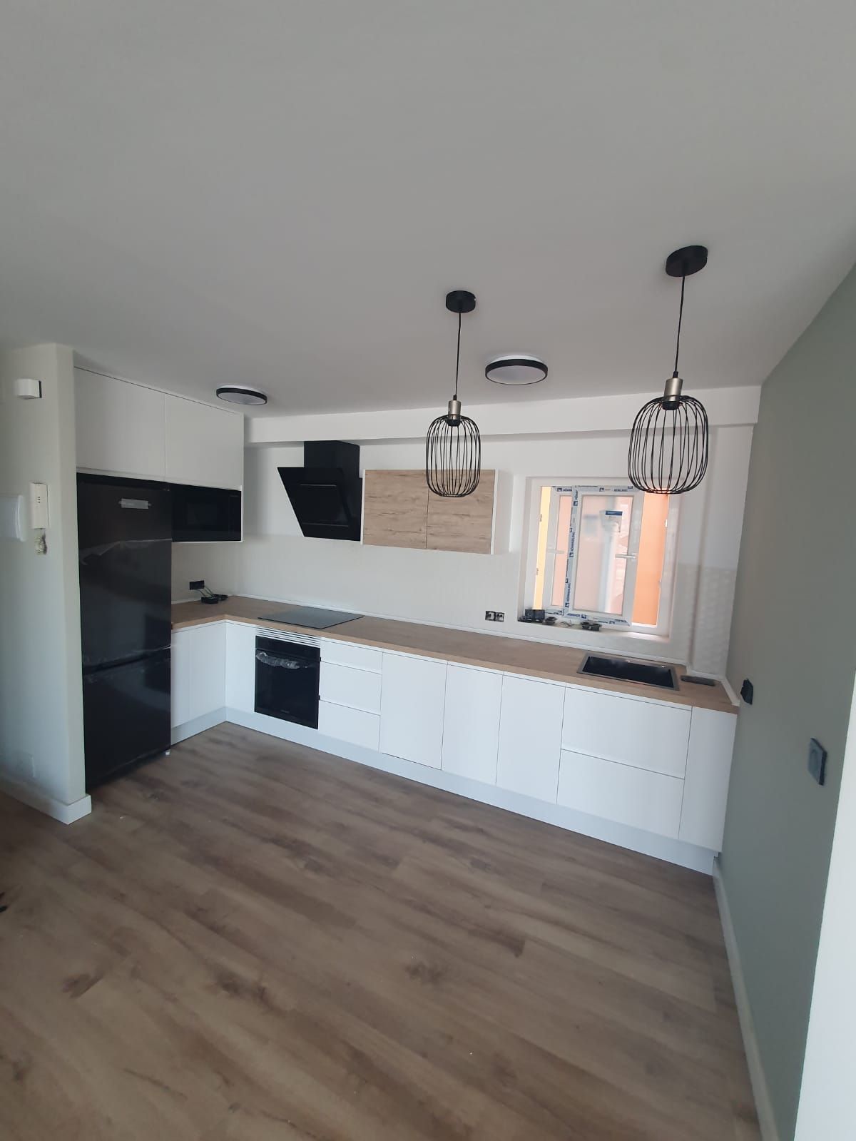 Una cocina con gabinetes blancos y un refrigerador negro.
