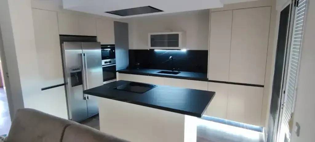 Una cocina con gabinetes blancos y una encimera negra.