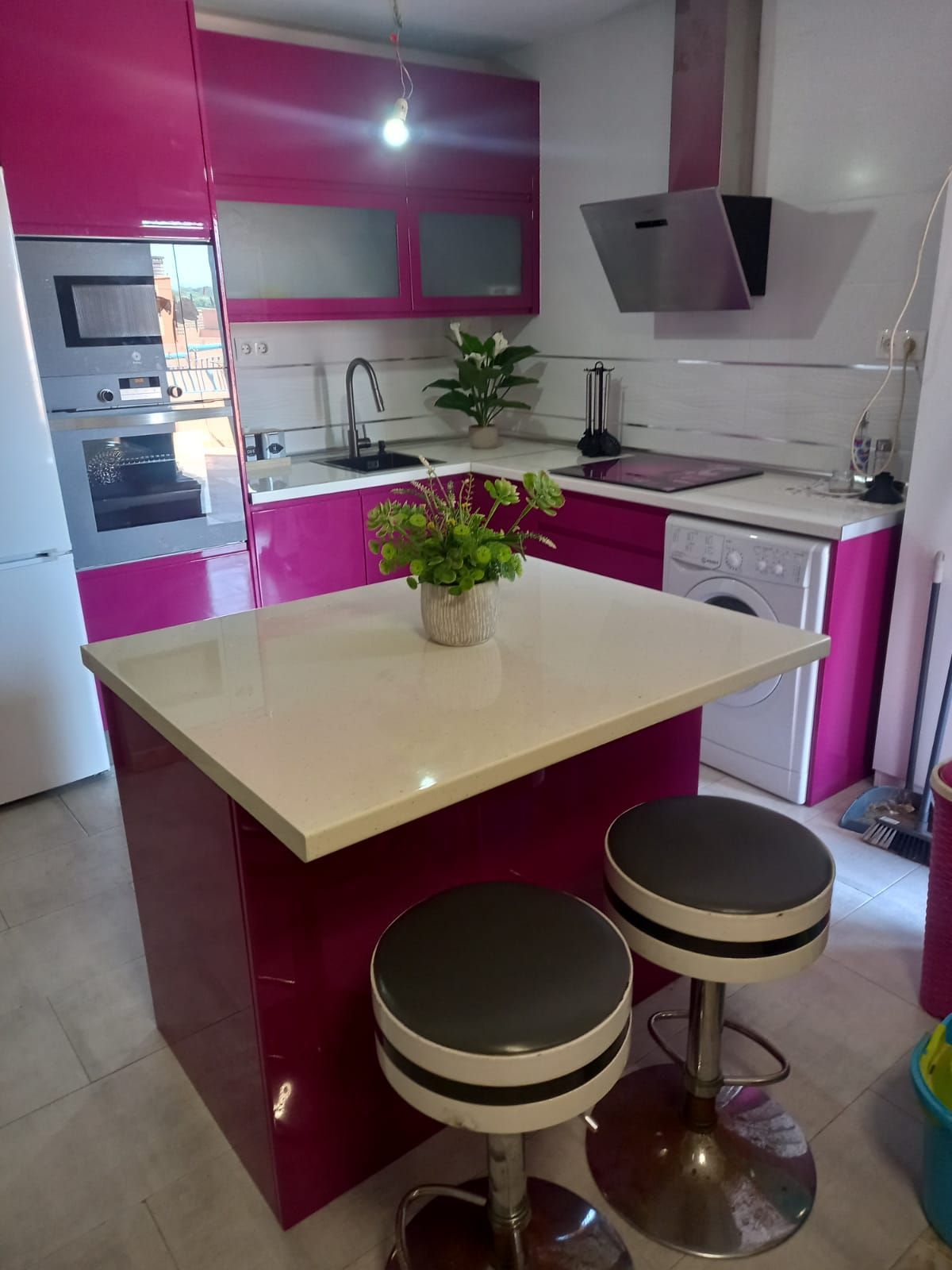 Una cocina con gabinetes rosas y una encimera blanca.