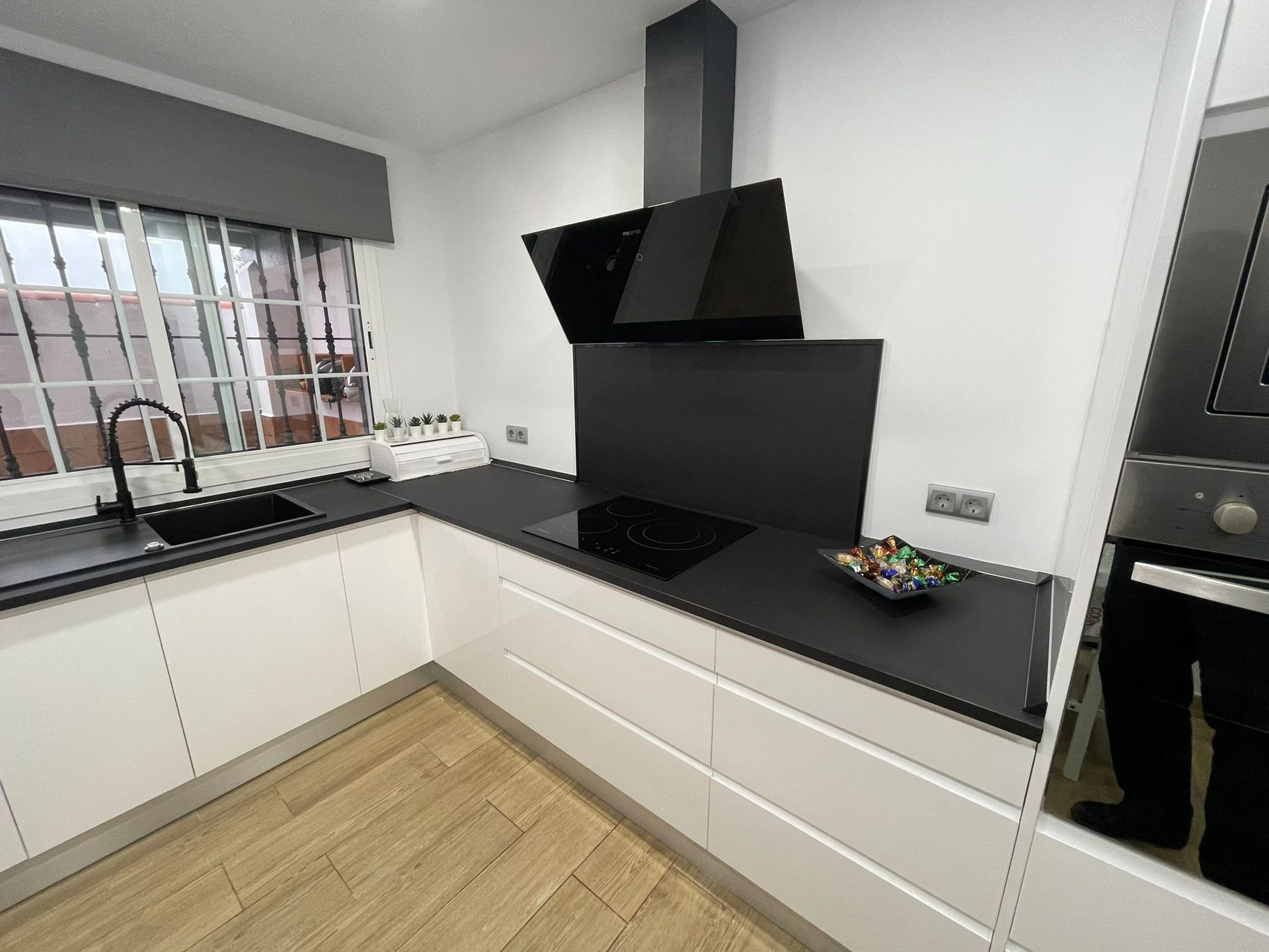 Una cocina con gabinetes blancos y encimeras negras.