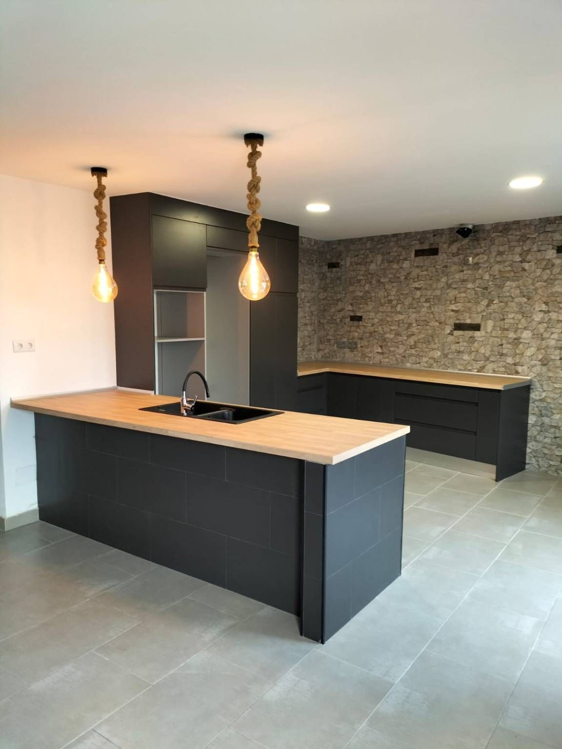 Una cocina con gabinetes negros y una encimera de madera.