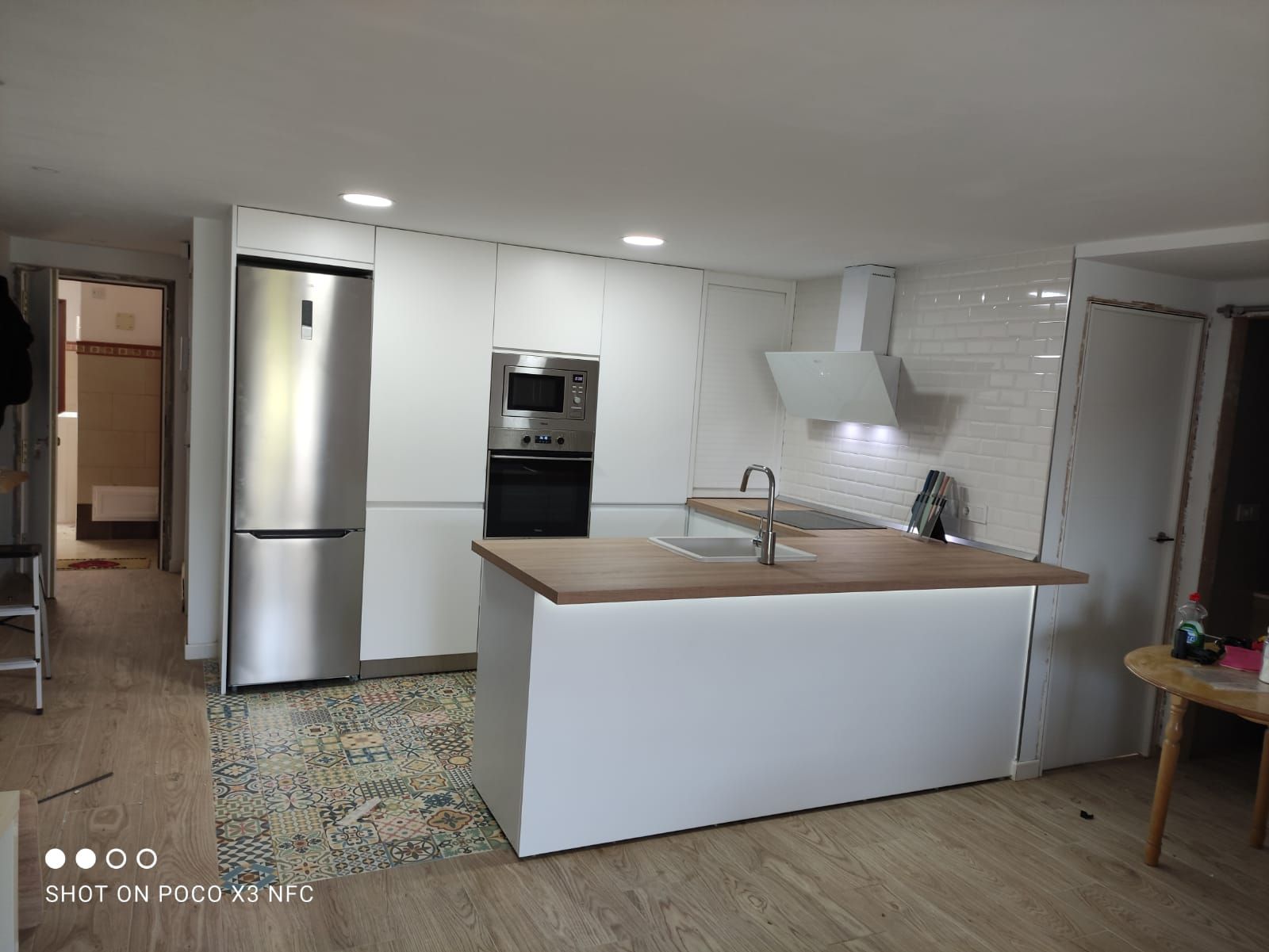 Una cocina con gabinetes blancos y electrodomésticos de acero inoxidable.