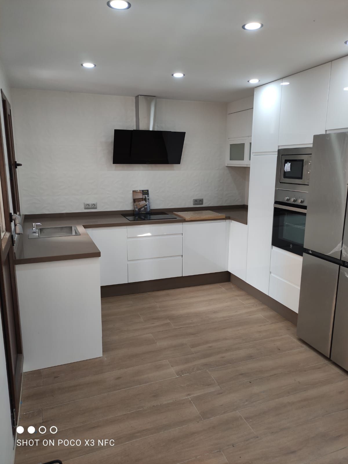 Una cocina con gabinetes blancos y electrodomésticos de acero inoxidable.