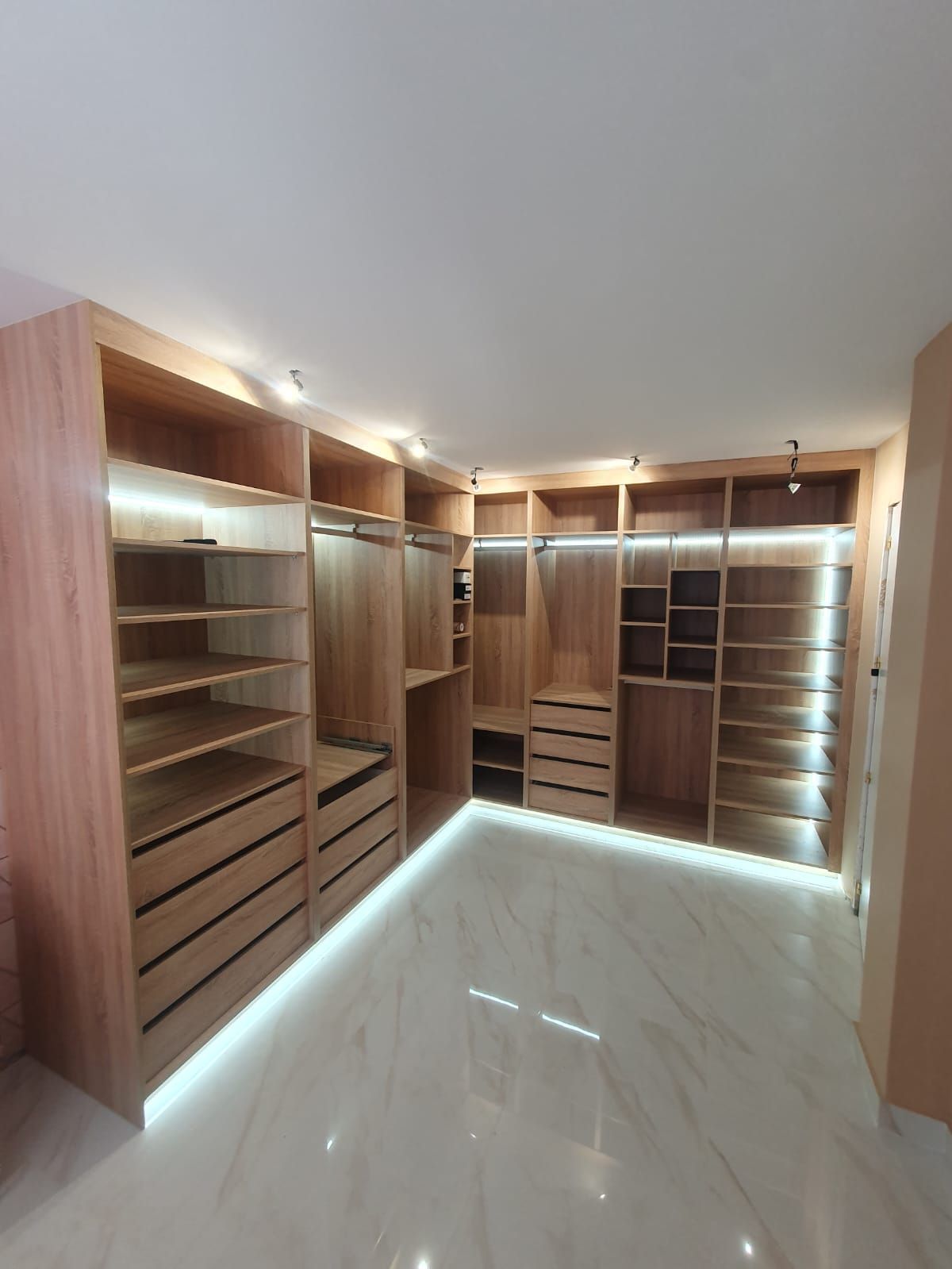 Un amplio vestidor con estantes y cajones de madera.