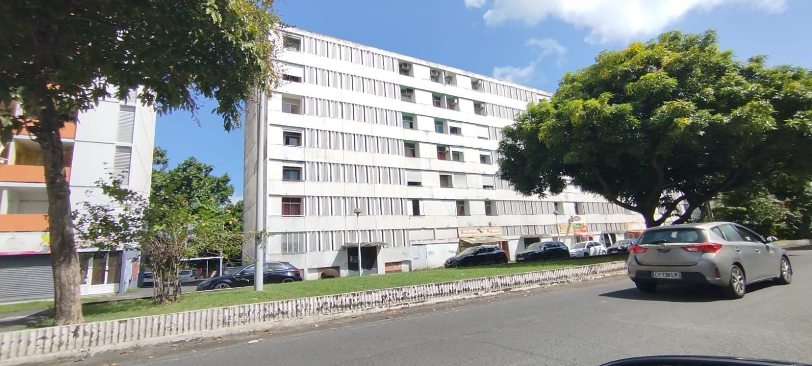 Façade blanche ornée de boiseries orange, d'un auvent décoratif et d'un ciel bleu au-dessus