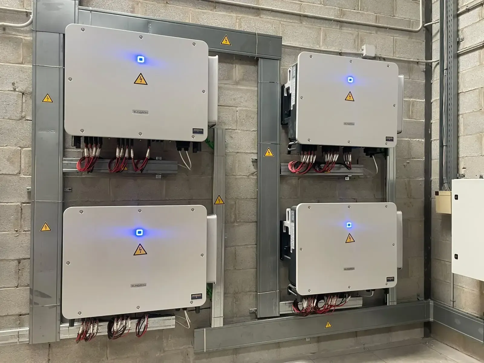 Cuatro cuadros eléctricos de control montados en la pared de una sala de instalaciones de hormigón.