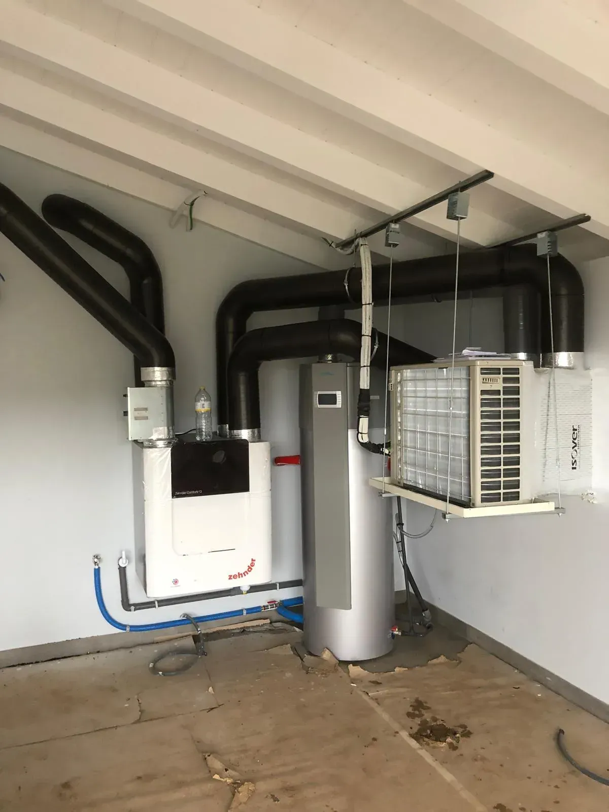Cuarto de instalaciones en el sótano con horno, calentador de agua, conductos y aire acondicionado de pared.
