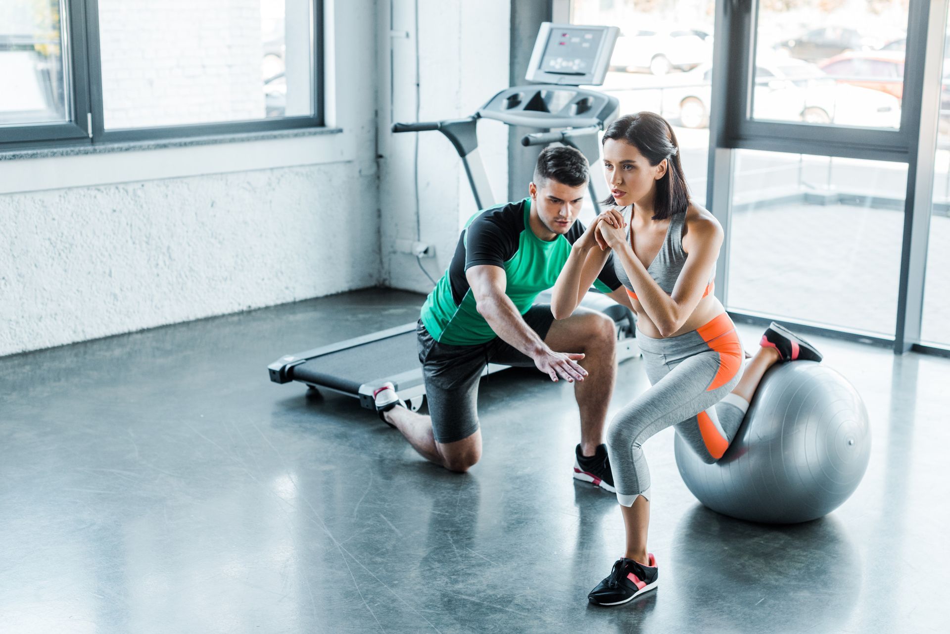 Un hombre y una mujer están sentados en una pelota de pilates en un gimnasio.