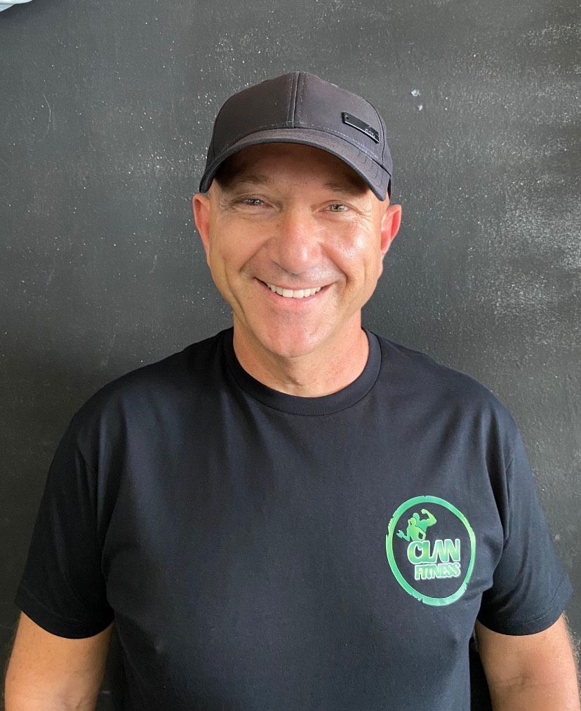 Un hombre que lleva un sombrero y una camisa negra sonríe para la cámara.