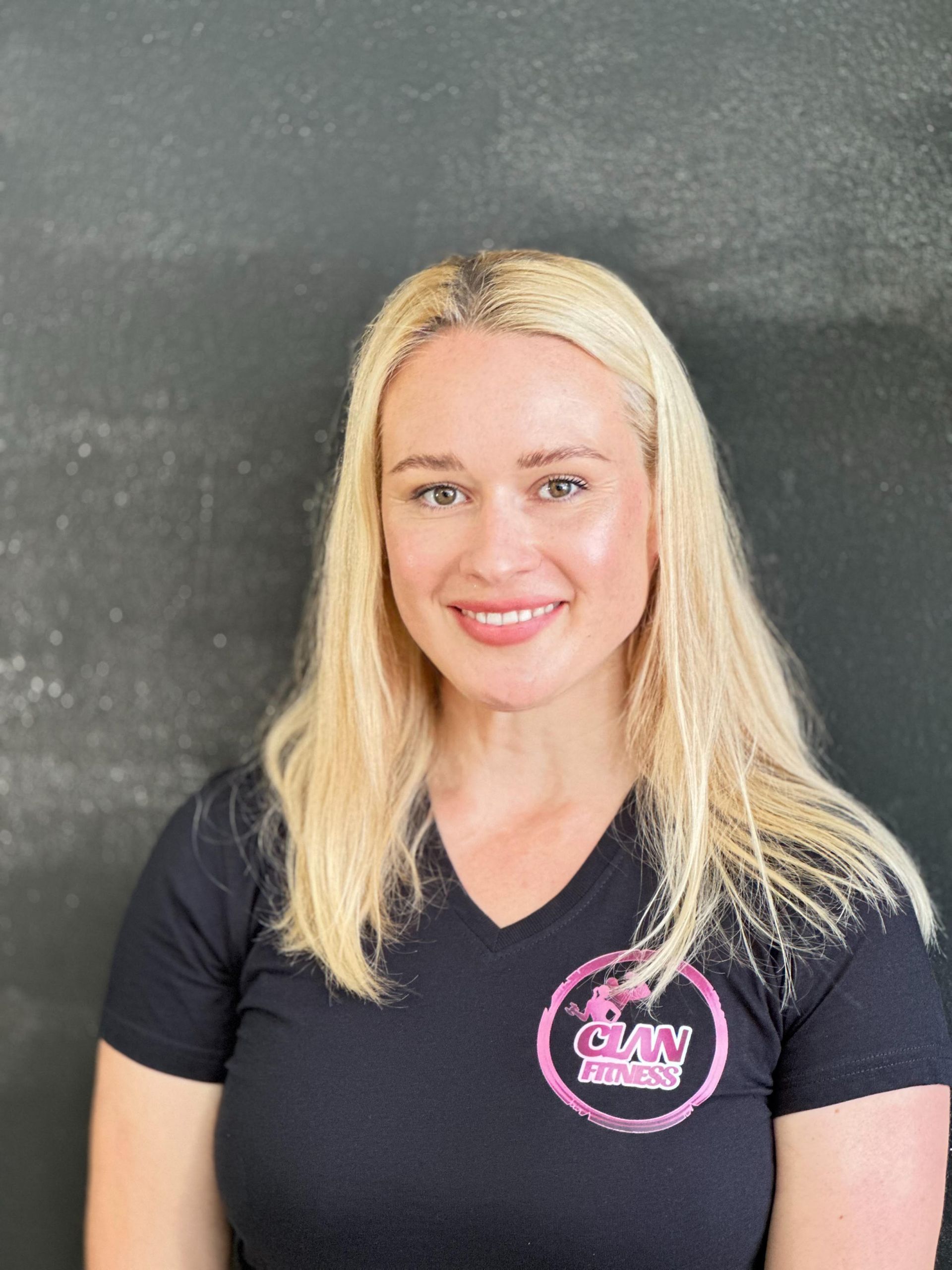 Una mujer que lleva una camiseta negra con un logo rosa.