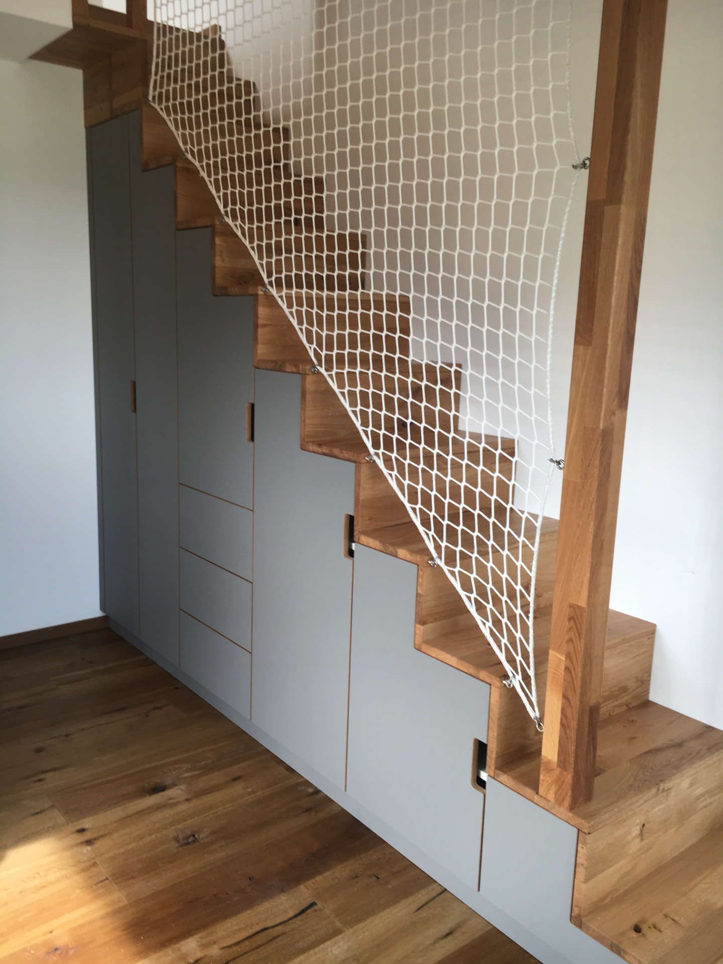 Offene Treppe mit Einbauschrank und Sicherungsnetz