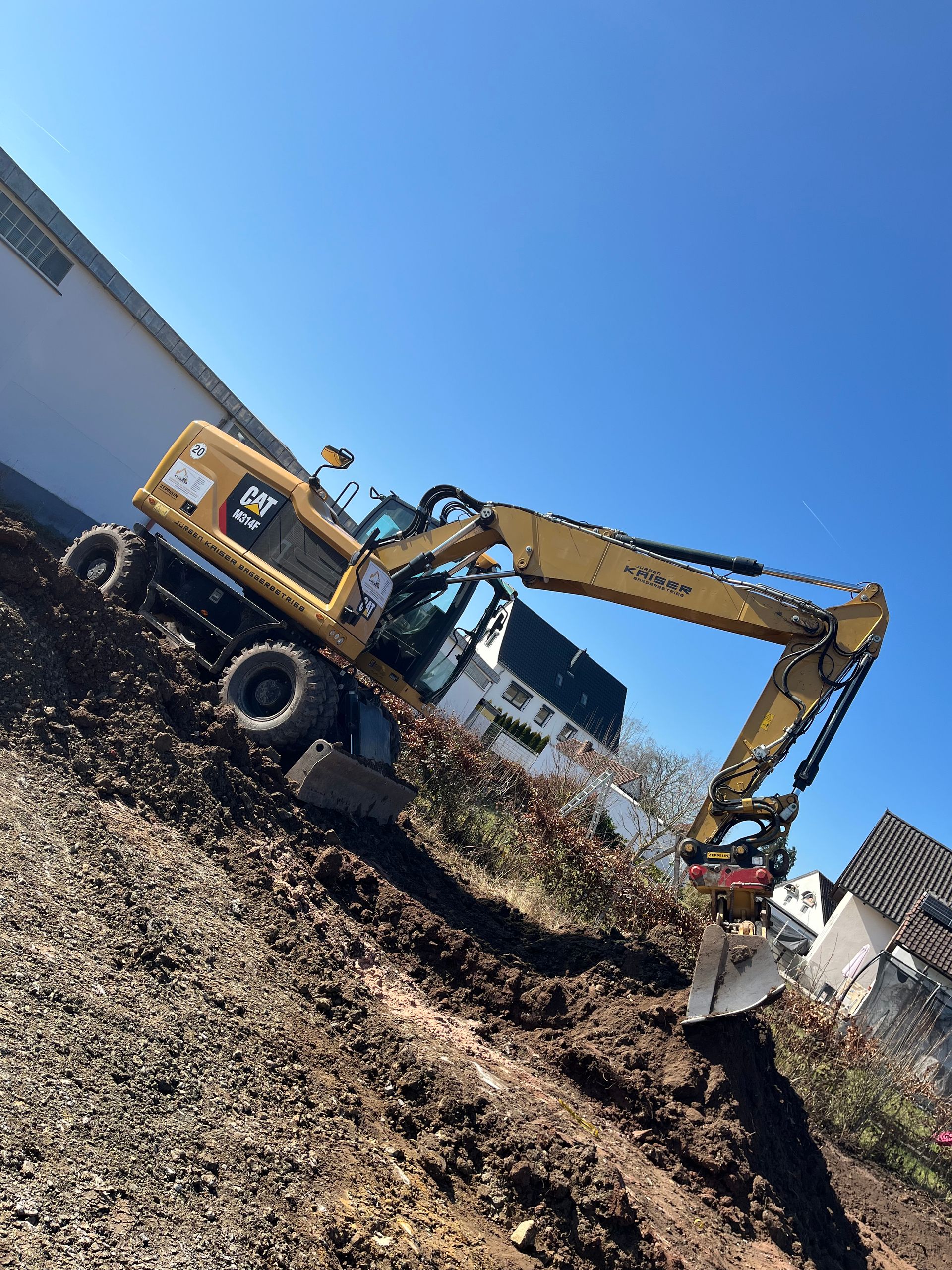 Baggerlader auf Baustelle – Ein orangefarbener Baggerlader fährt auf einer Straße, ideal für Bau- und Erdarbeiten.