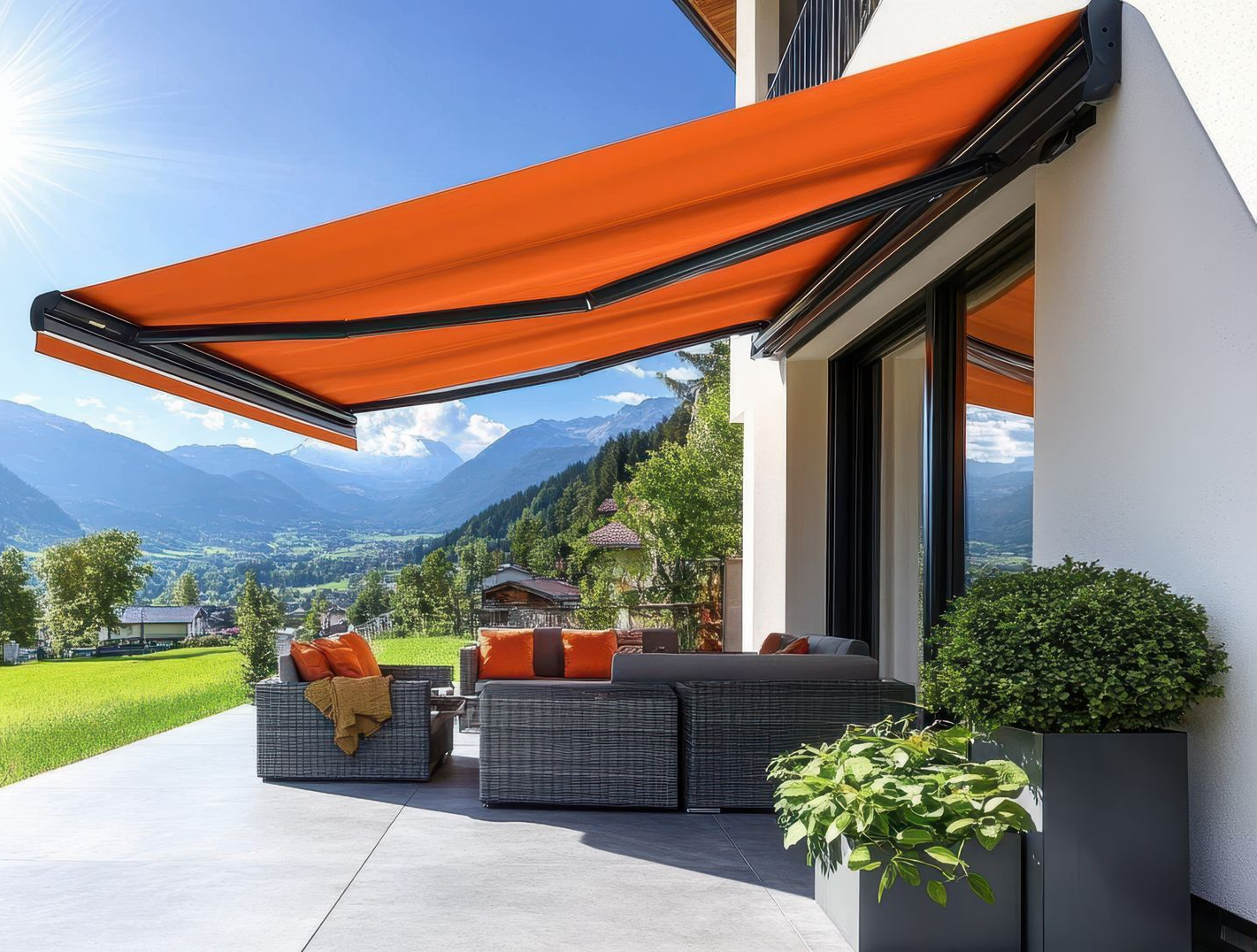 Store banne rétractable orange au-dessus d'une terrasse avec vue sur la montagne.