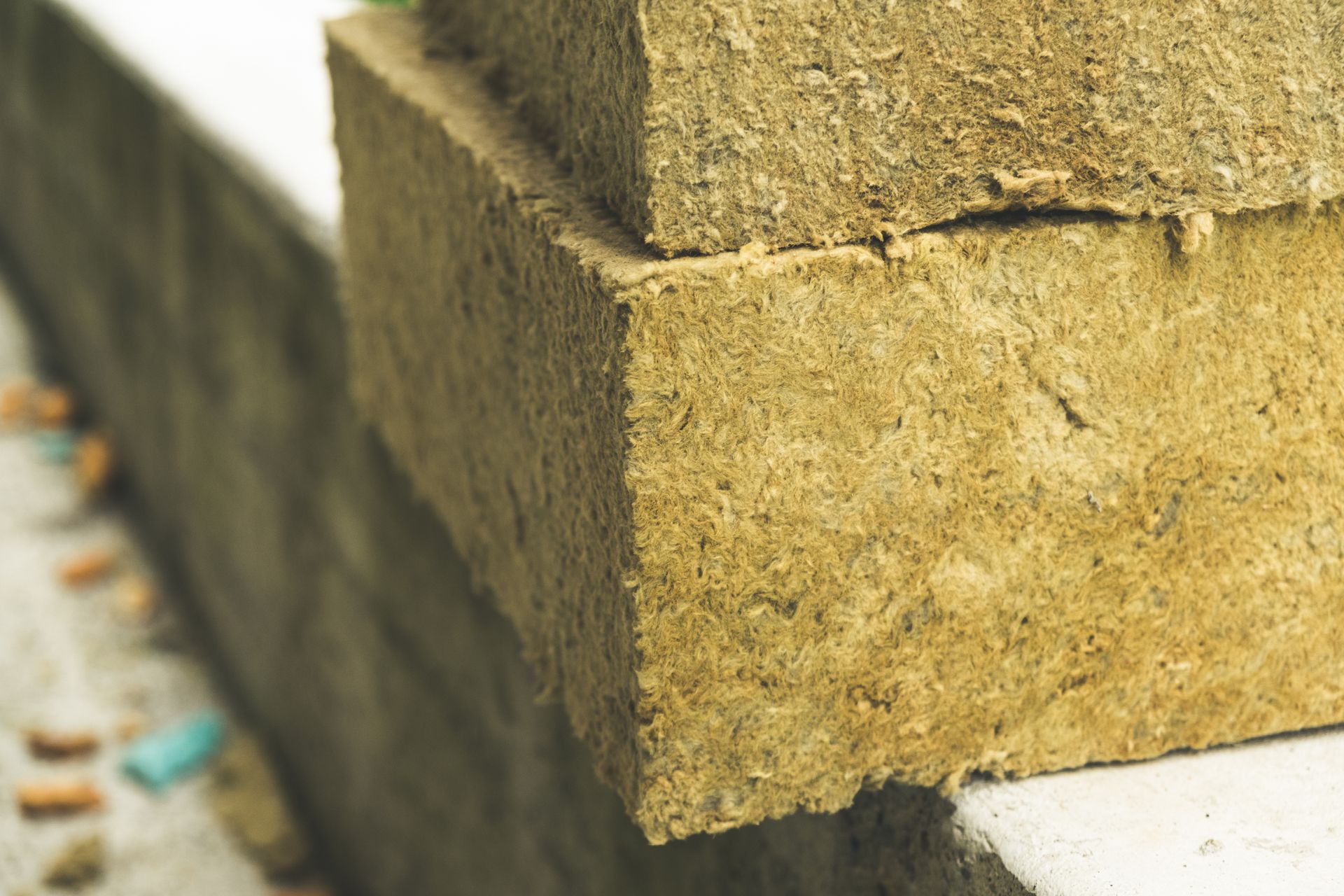 Gros plan sur des blocs d'isolation en laine de roche beige, rectangulaires et empilés.