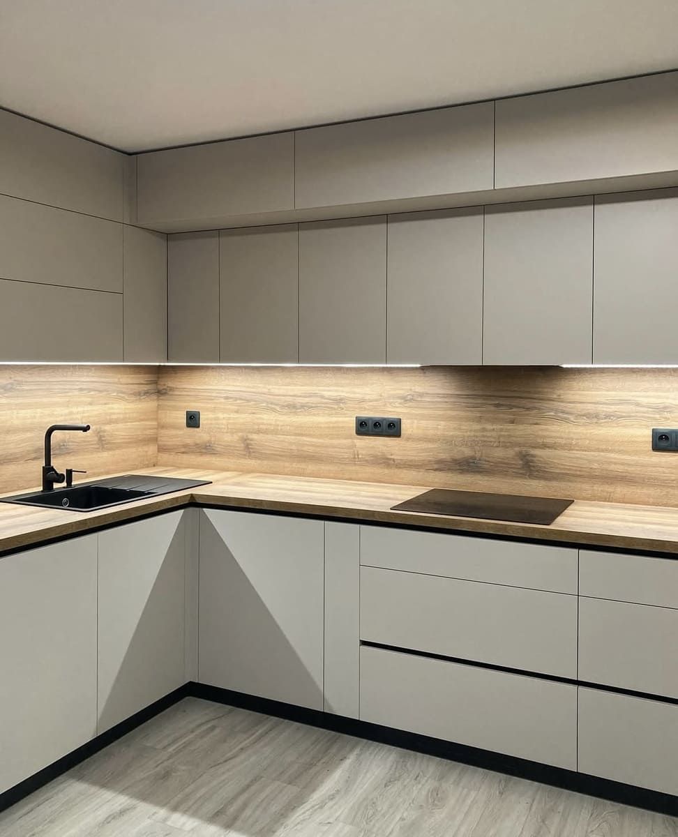 Cocina moderna con gabinetes gris claro, encimeras de madera y detalles en negro.