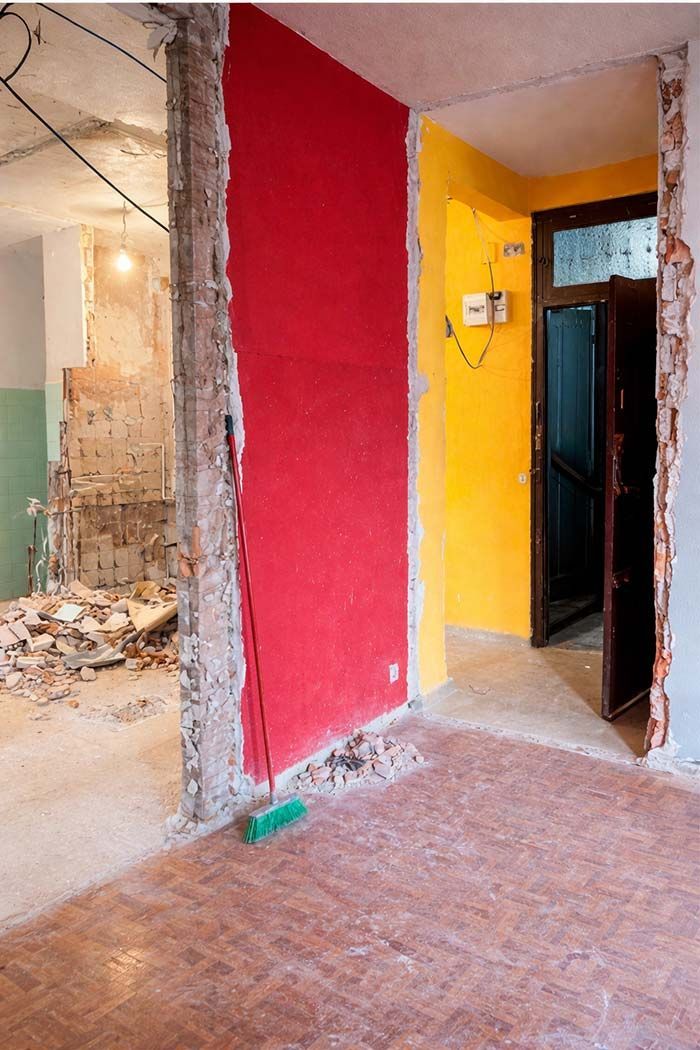 Cocina con gabinetes de madera, mesa de comedor y sofá seccional rojo.