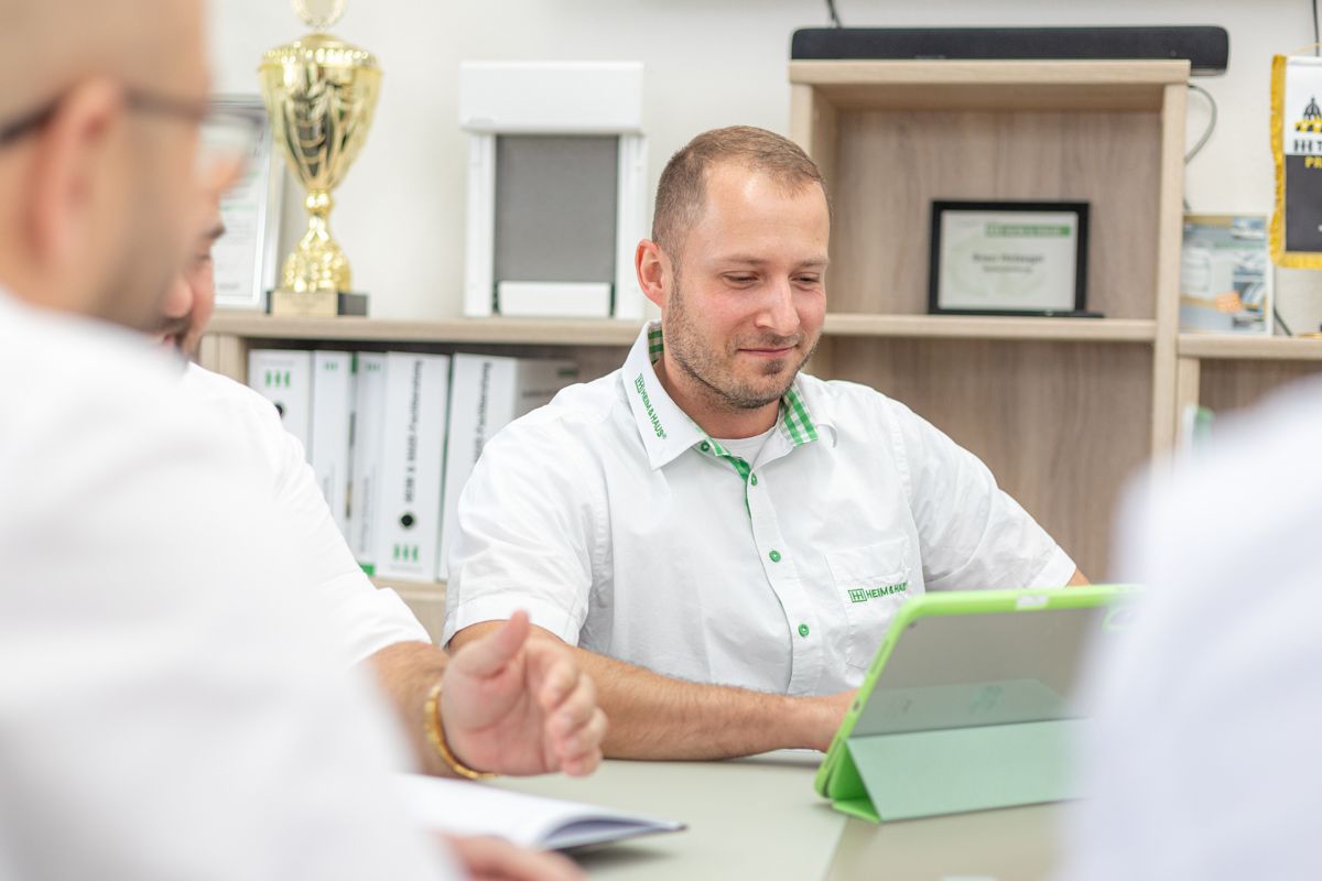 Eine Gruppe von Männern sitzt an einem Tisch und schaut auf einen Tablet-Computer.