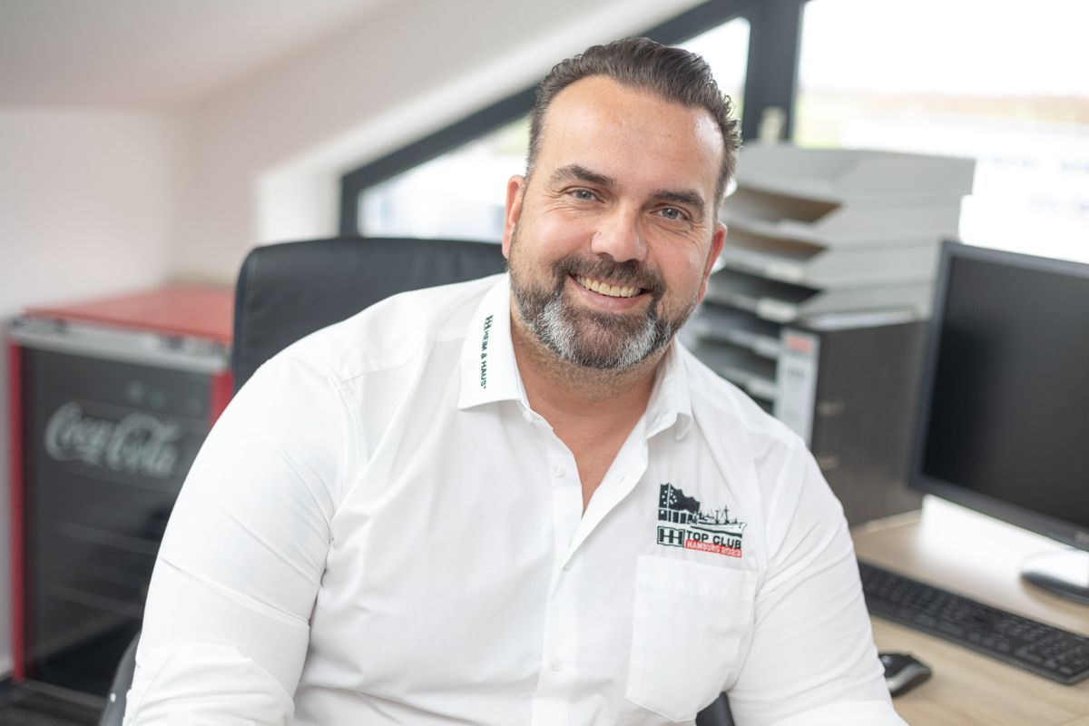 Ein Mann in einem weißen Hemd sitzt auf einem Stuhl.