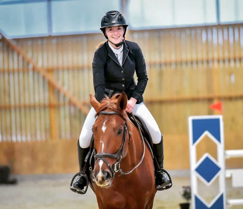 Cavalière souriante sur le dos de son cheval marron
