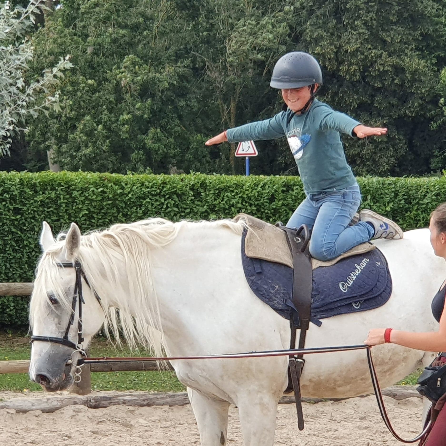 Enfant souriant et à genoux sur le dos d'un poney blanc