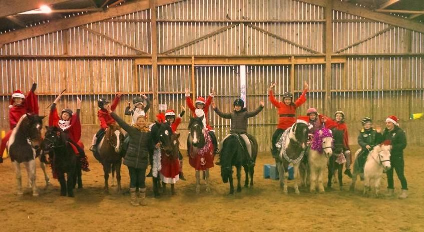 Poneys déguisés pour Noël avec des enfants sur le dos qui lèvent les bras