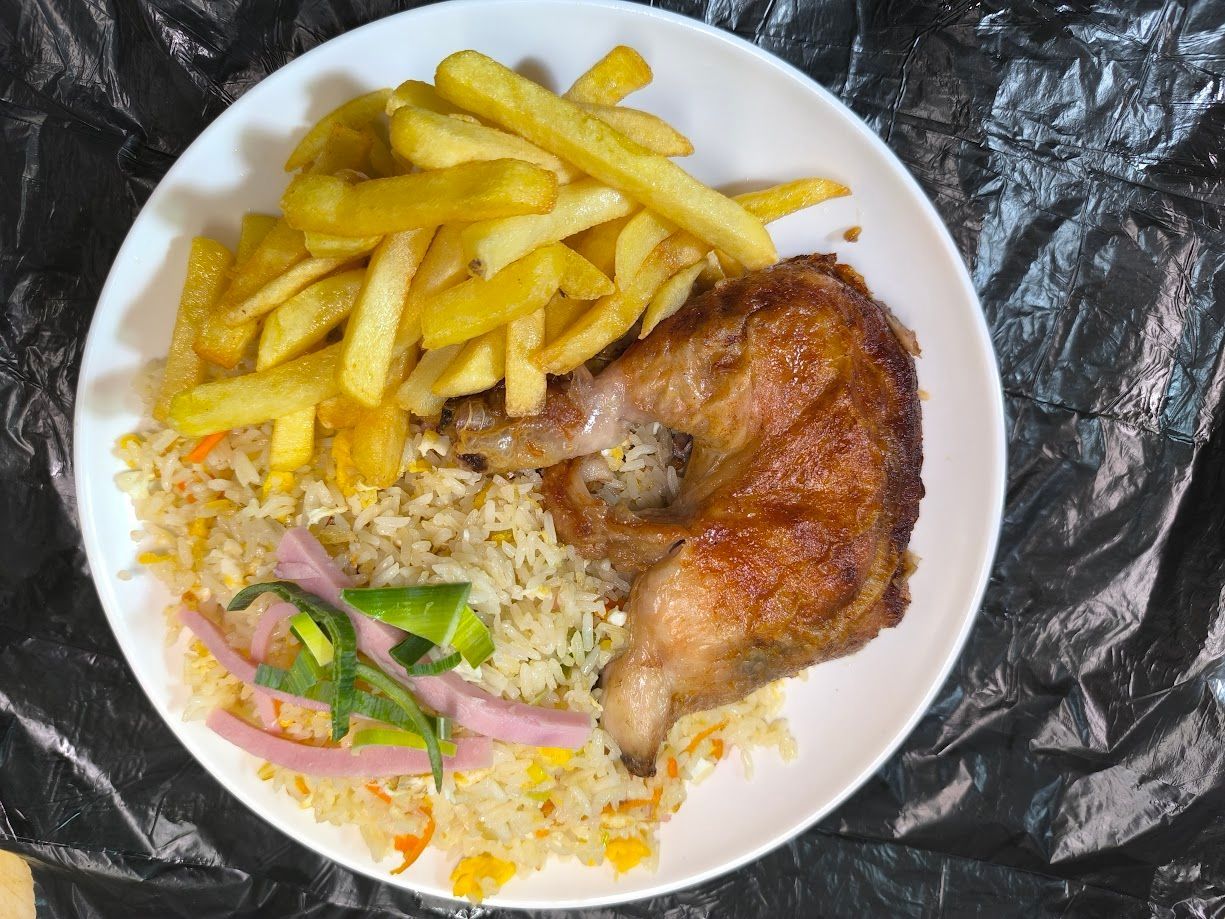 Plato de comida: muslo de pollo crujiente, patatas fritas, arroz y verduras encurtidas.