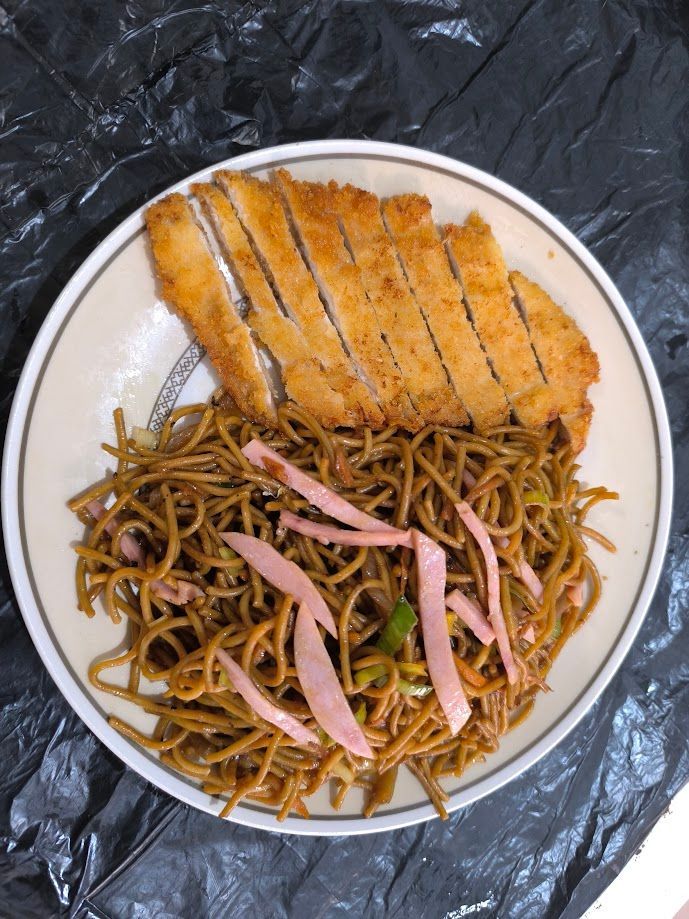 Plato de fideos yakisoba con chuleta de cerdo empanizada en rodajas y jengibre encurtido.