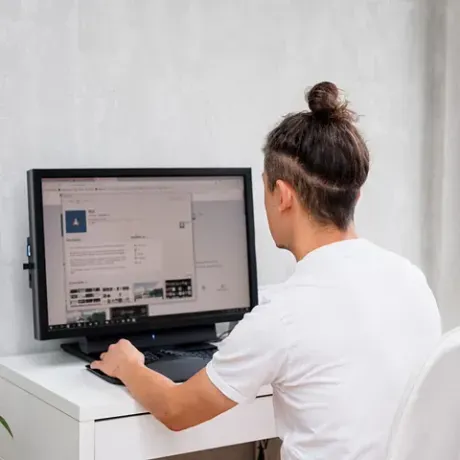 Un hombre está sentado en un escritorio frente a un monitor de computadora.