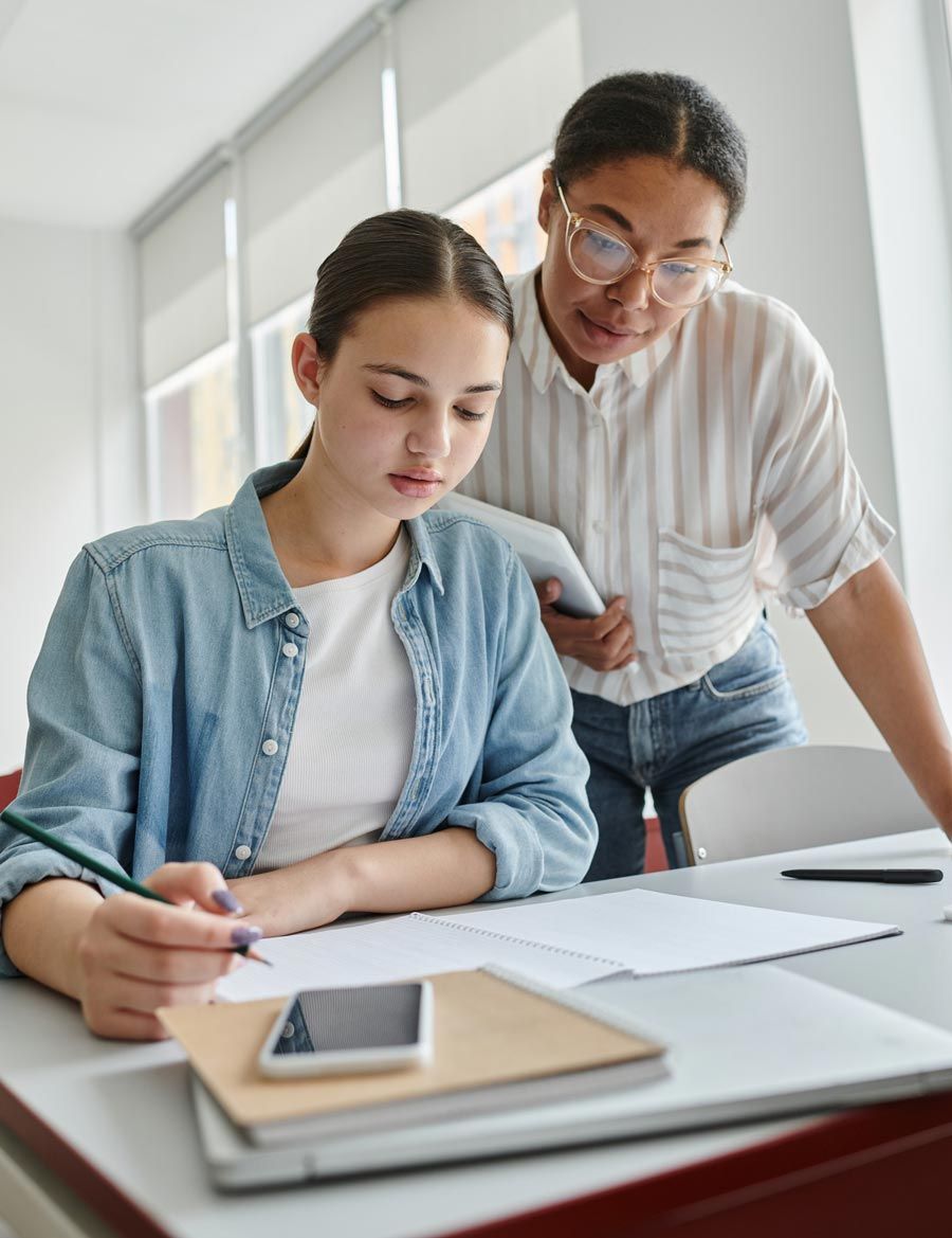 Una mujer está ayudando a una niña con su tarea.