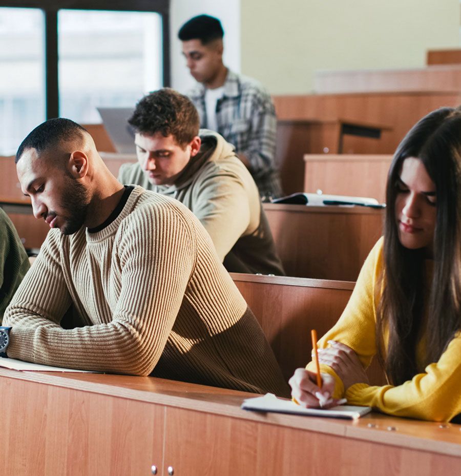 Un grupo de personas están sentadas en escritorios en una sala de conferencias.