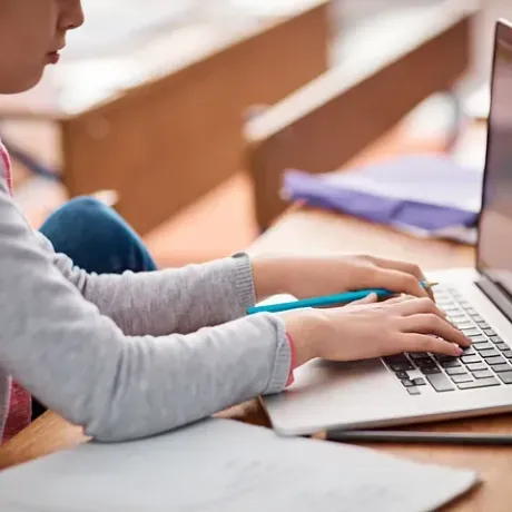 Una niña está escribiendo en una computadora portátil.