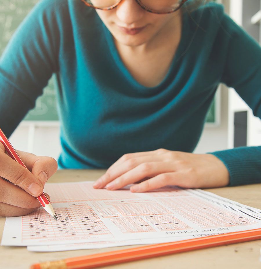 Una mujer está sentada en una mesa tomando un examen con un lápiz.