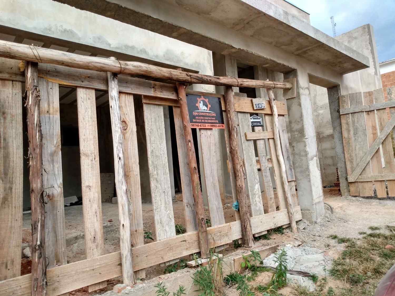 Barricada de madera desgastada que bloquea una puerta en el exterior de un edificio dañado, con un cartel de advertencia.
