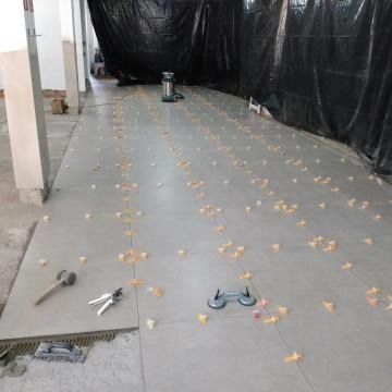 Habitación en construcción con suelo de hormigón, láminas de plástico negro y herramientas/materiales dispersos.