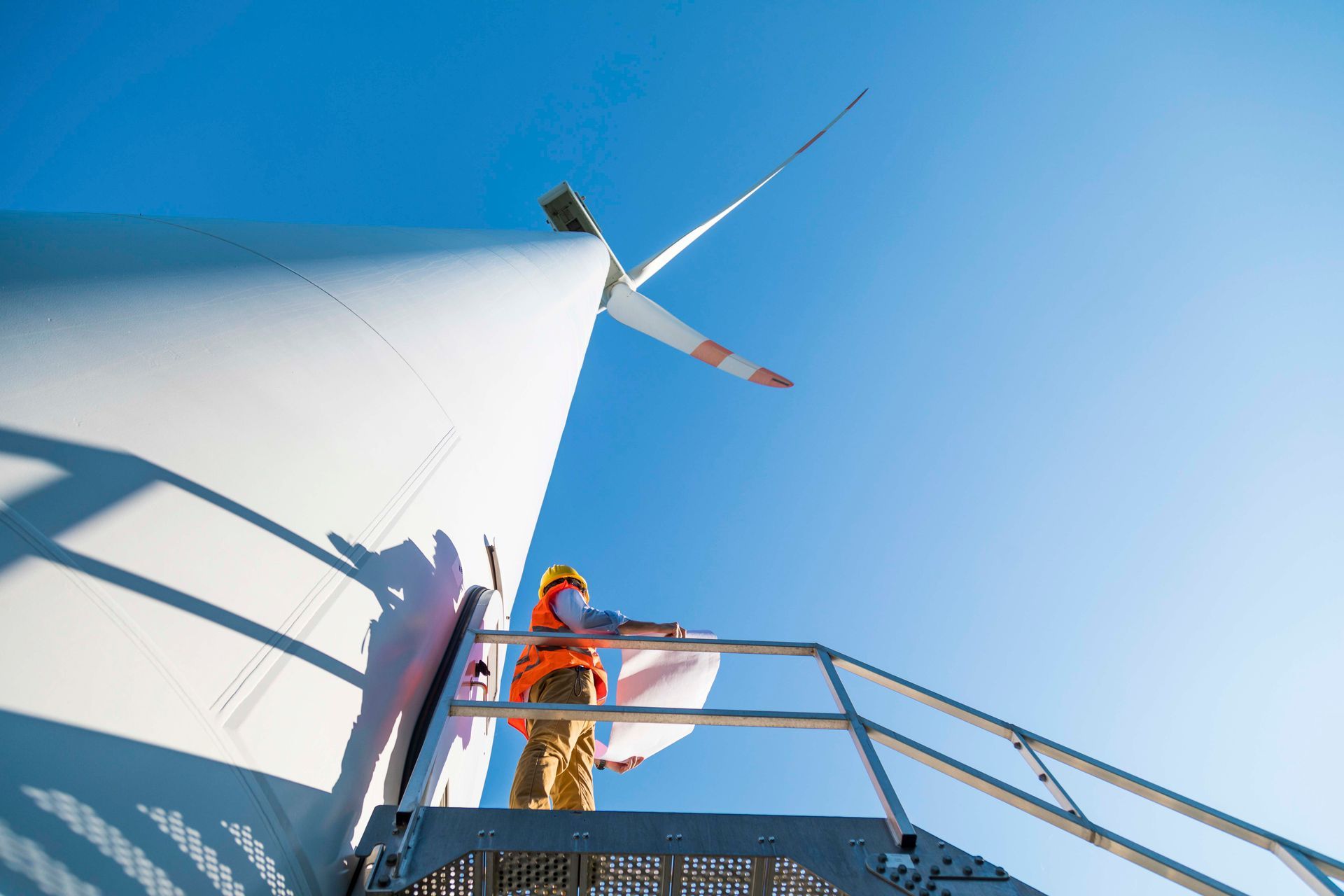 Ein Mann steht auf einer Treppe neben einer Windkraftanlage .
