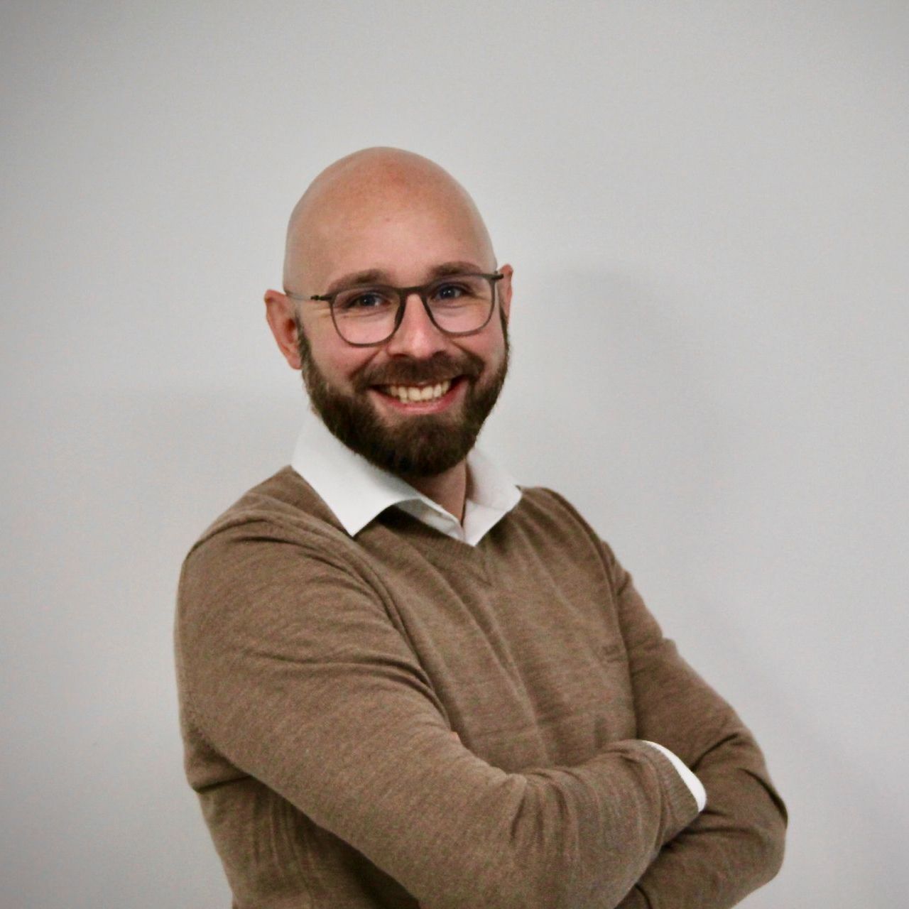 ein mann mit brille und braunem pullover lächelt