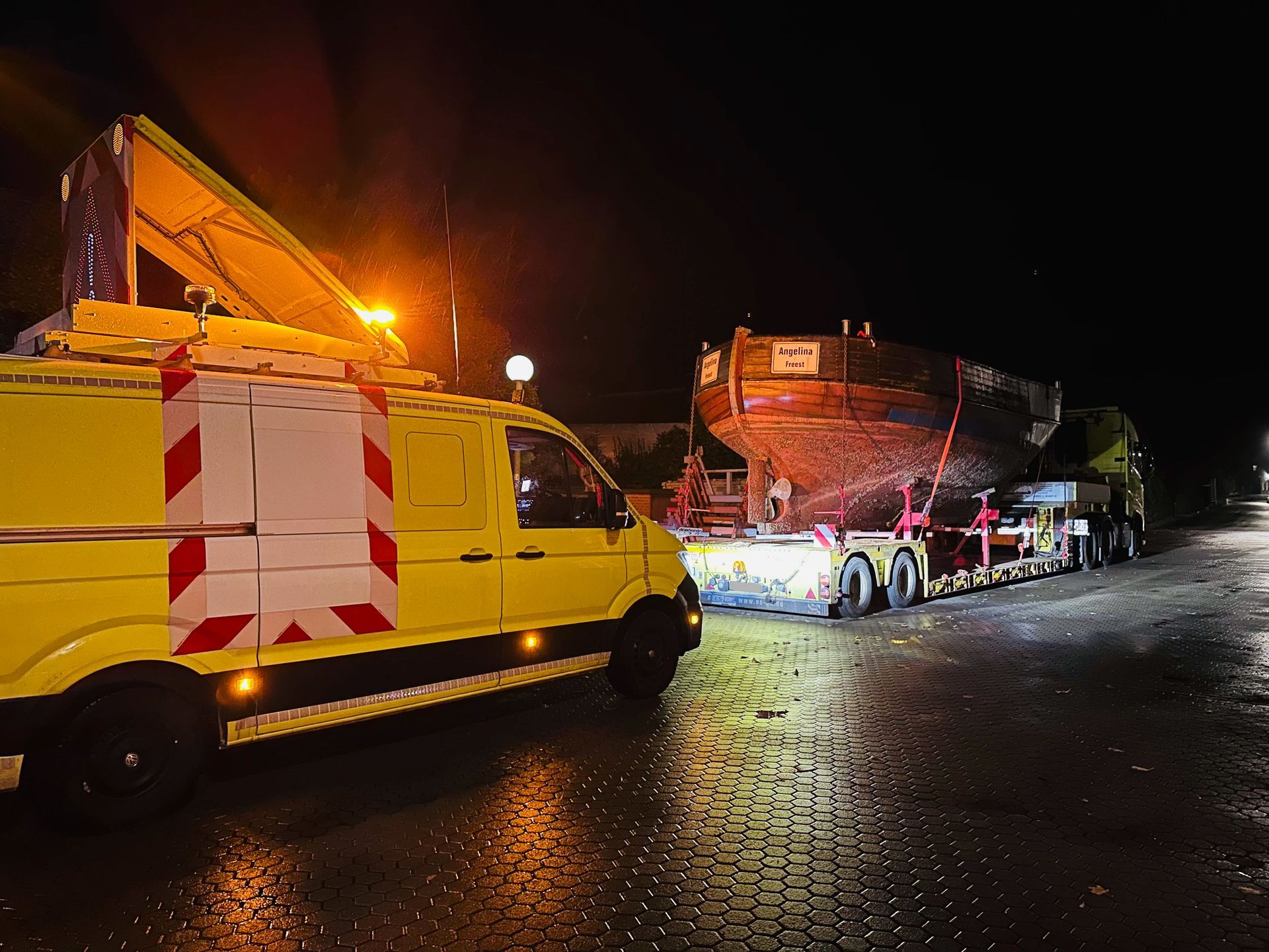 ein gelber lkw steht neben einem lkw mit einem boot darauf
