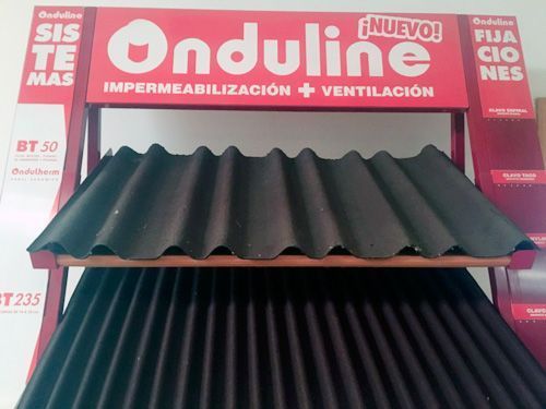 Una exhibición de techos corrugados negros con un letrero rojo que dice onduline