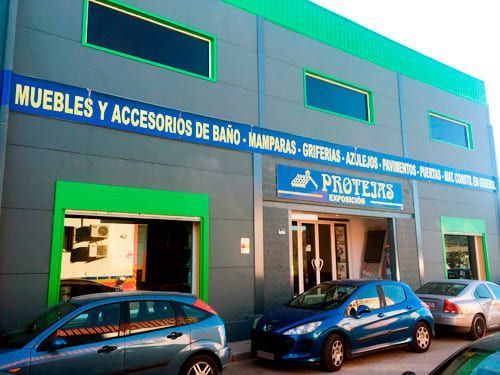 Los coches están aparcados delante de un edificio que dice muebles y accesorios de baño.