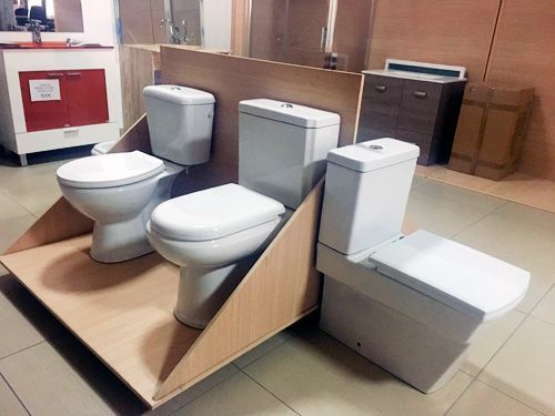 Hay tres inodoros sobre un estante de madera en un baño.