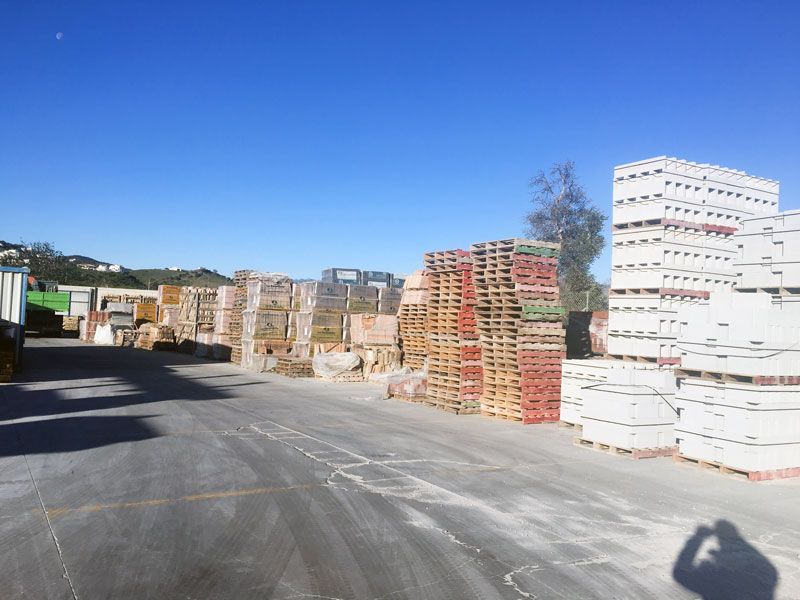 Hay muchos palets apilados uno encima del otro en un estacionamiento.