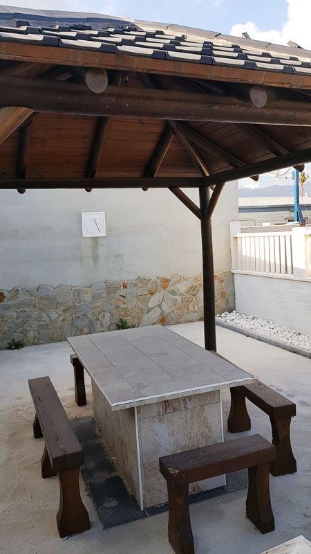 Hay una mesa y bancos debajo de un cenador.