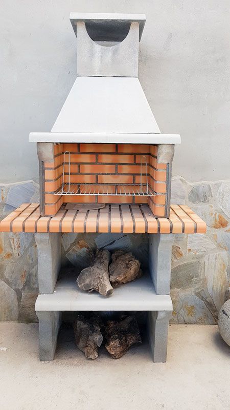 Una parrilla de ladrillo está situada delante de una pared de piedra.